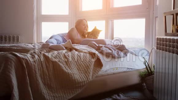 美丽浪漫的黑发女人躺在窗边与她可爱的缅因州考恩猫在惊人的日落慢慢慢慢视频的预览图