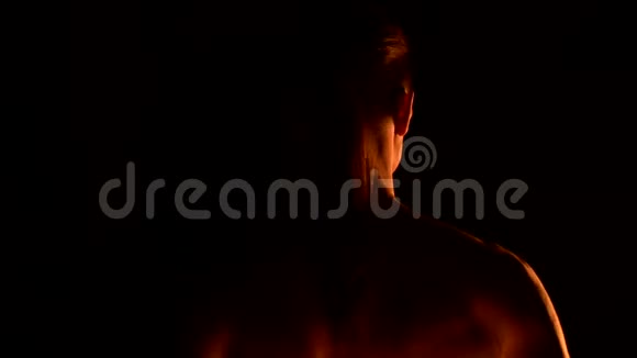 特写后景低调黑色的夜晚年轻的男性长发裸露的躯干在室外旋转燃烧的火炬视频的预览图