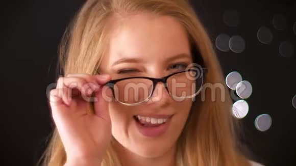 戴着浅色长发眼镜的白种人女性可爱的肖像她站在黑色背景上微笑着视频的预览图