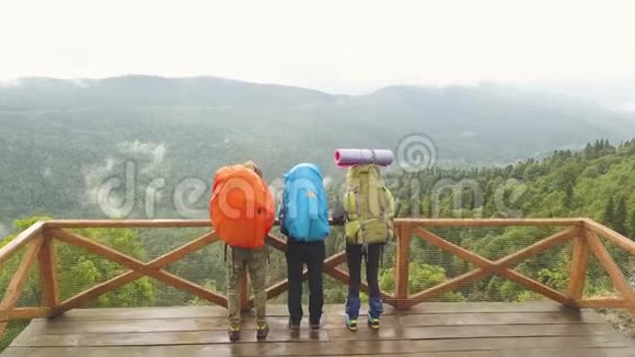 徒步旅行者背着背包站在山顶上的绿色森林鸟瞰图视频的预览图