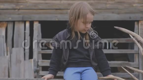 漂亮时尚的小村庄女孩坐在木制建筑上视频的预览图