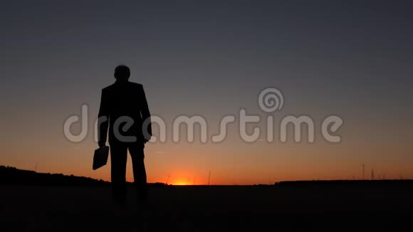 在蓝天的背景下商人用公文包在日出时行走视频的预览图