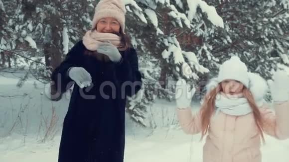快乐的妈妈和女儿在冬天的树木背景下跳舞而雪视频的预览图