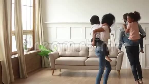 快乐的非洲父母驮着孩子在家玩视频的预览图
