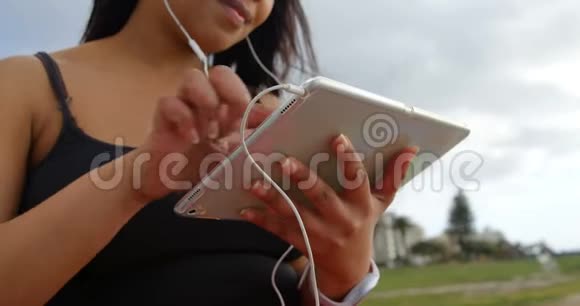 公园4k残疾妇女在数码平板电脑上听音乐特写视频的预览图