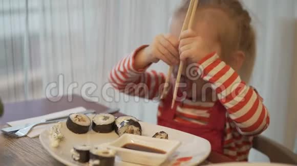 一个小女孩吃寿司她用木筷拿了一卷视频的预览图