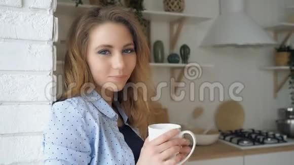 头发松松的女孩喝茶微笑着靠在砖墙上视频的预览图