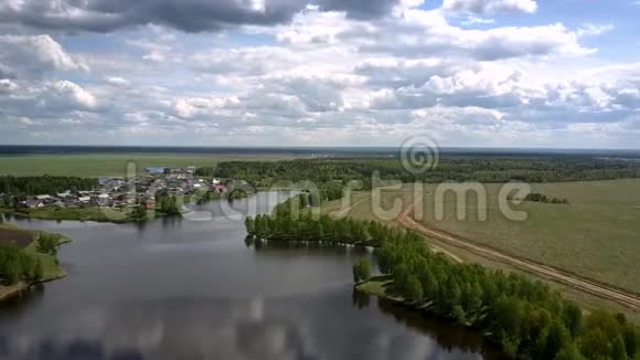 小村庄的屋顶平静的河岸附近一望无际的田野视频的预览图