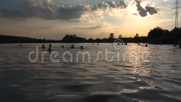 城市海滩人们在日落时洗澡一条电线穿过湖面视频的预览图
