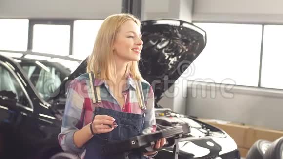 乐观积极的女性机械师带着数码平板电脑看相机视频的预览图