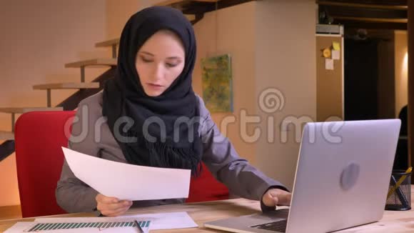 阿拉伯青年女性办公室工作人员的特写肖像用笔记本电脑分析图表上的数据并做笔记视频的预览图