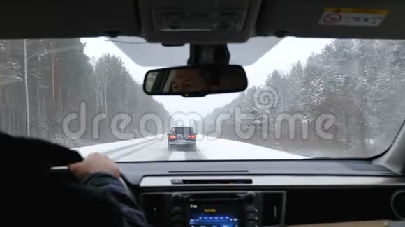 一个人开着一辆车穿过一条冬天白雪覆盖的道路视频的预览图