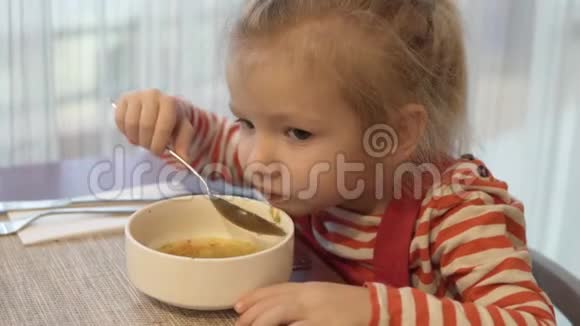小女孩吃蔬菜汤她坐在桌边端着一勺汤视频的预览图