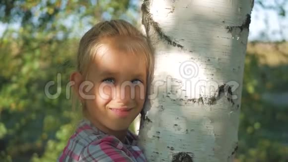 十几岁的女孩靠在太阳下的桦树上合上看着摄像机视频的预览图