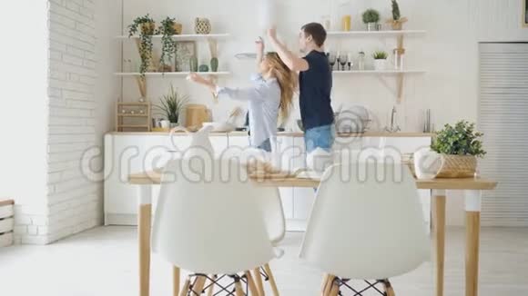 现代厨房的餐桌上快乐的男人女人跳舞视频的预览图