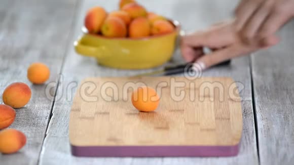 女性用刀子在切割板上切杏的特写烹饪素食视频的预览图
