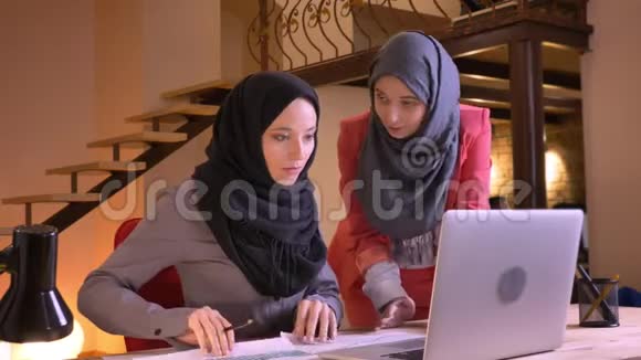 两位年轻成功的穆斯林女商人在笔记本电脑前讨论数据和图表的特写照片视频的预览图
