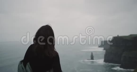 漂亮的女孩在悬崖顶上有一个冥想亭她自己她站在后面的相机看视频的预览图