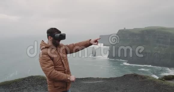 一位年轻的游客在悬崖顶的VR时间他用VR探索这个地方感觉印象深刻站在上面视频的预览图