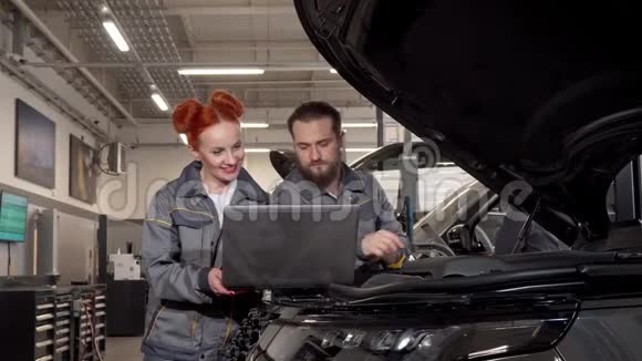 专业的汽车机械师在车库的汽车诊断过程中使用笔记本电脑视频的预览图
