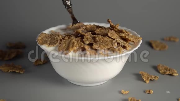 一个男人在一个白色的盘子里搅拌一勺麦片粥和一杯牛奶视频的预览图