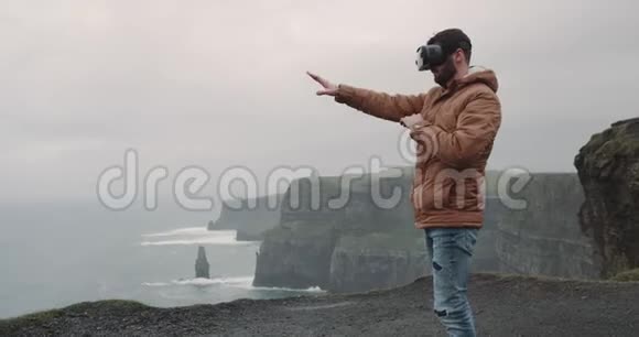 游客使用虚拟现实兴高采烈在悬崖等令人惊叹的地方旅行他站在山顶上视频的预览图