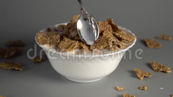 一个男人在一个白色的盘子里搅拌一勺麦片粥和一杯牛奶视频的预览图