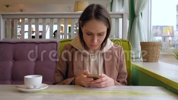 女性在咖啡馆里使用智能手机视频的预览图