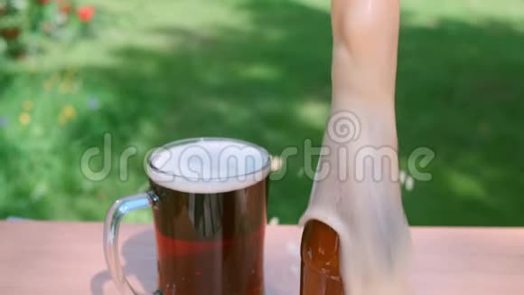 新鲜的深色啤酒和瓶子泡沫在绿色花园视频的预览图