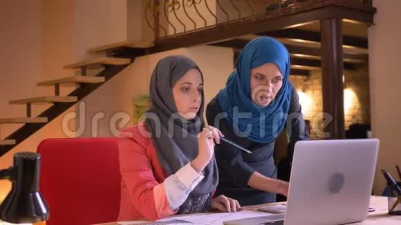 两位身穿头巾的阿拉伯年轻女商人为图中的信息争吵的特写照片视频的预览图