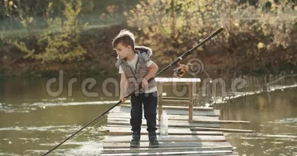 小有趣的男孩教如何在湖上捕鱼他拿着一根大鱼竿视频的预览图