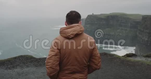 散步的人来到悬崖岸边他兴高采烈地在那里令人惊叹的风景在莫赫悬崖的顶部视频的预览图