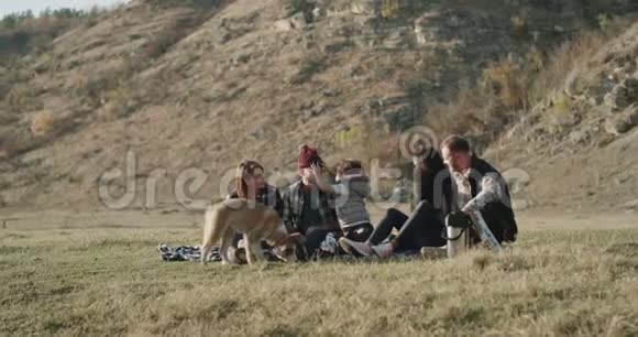 阳光明媚的一天两个家庭一起野餐小男孩和一个好朋友和一只小哈士奇狗玩耍视频的预览图