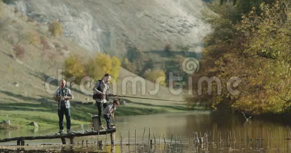 一个小男孩和两个人在大自然的湖边钓鱼视频的预览图