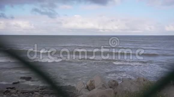 在美丽的海岸线上穿过金属网的风景海浪在海岸上飘落视频的预览图