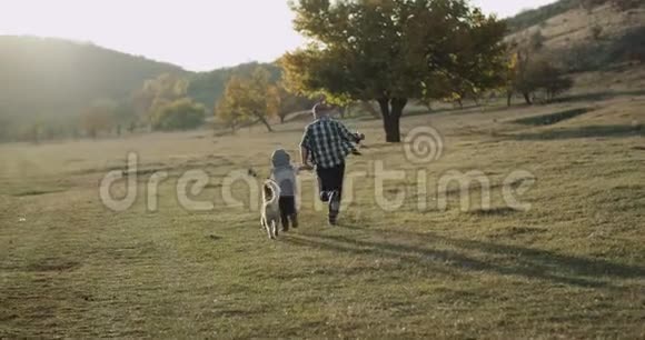 令人惊叹的家庭日爸爸和他的儿子一起跑在他们的哈士奇狗旁边的自然美丽惊人的景色视频的预览图