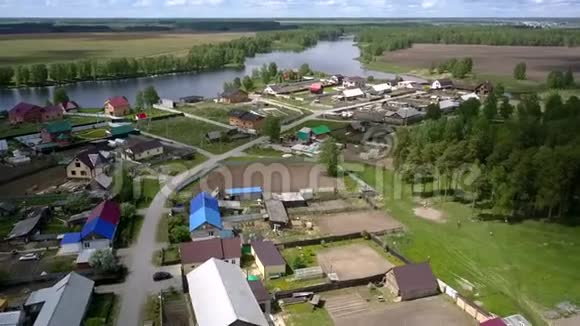 近蓝色平静的河流和棕色田野的现代村庄视频的预览图