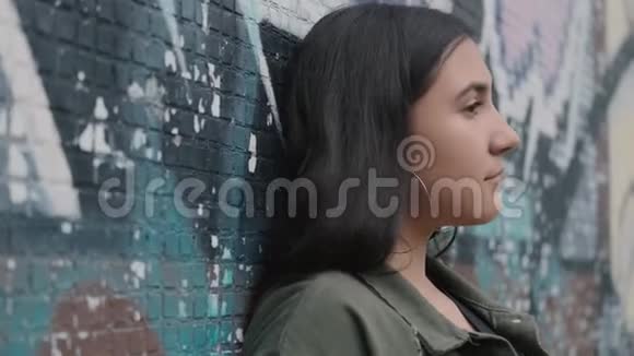 年轻时髦的黑发女孩在墙边涂鸦视频的预览图