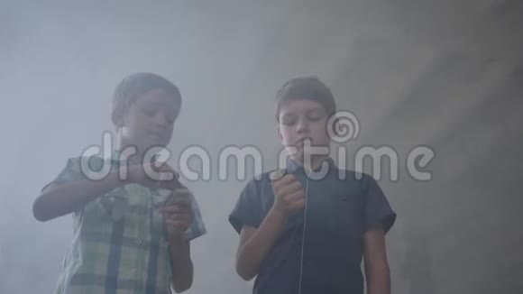 两个小男孩在一个烟雾弥漫的废弃房间里一个男孩拿着燃烧的火柴第二个男孩拿着燃烧的打火机视频的预览图