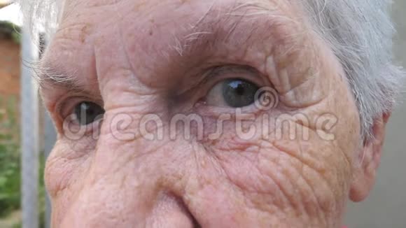 幸福的老妇人微笑着看着外面的镜头的肖像一张白发苍苍的布满皱纹的脸视频的预览图