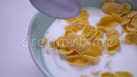 特写镜头的甜蜜早餐碗玉米粉麦片和牛奶用手蘸一勺美味的美餐视频的预览图