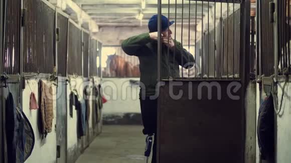 在马厩里残疾人戴着头盔骑马他走着靠在拐杖上穿过马厩人类视频的预览图