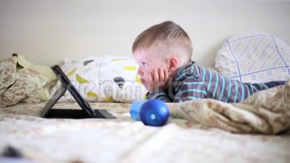躺在床上看着平板电脑的小男孩视频的预览图
