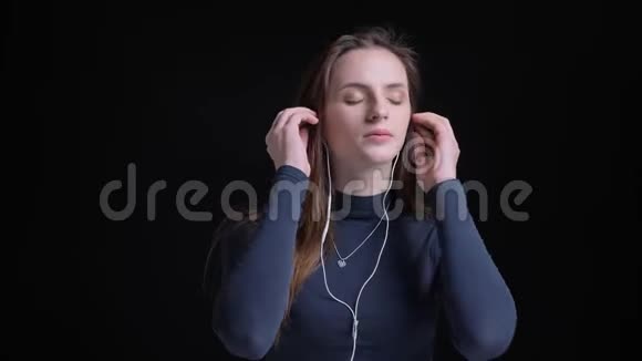 年轻苗条的白种人白种人女孩用耳机听音乐和满意地跳舞的肖像视频的预览图