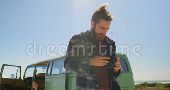 阳光明媚的4k天男人用数码相机看照片视频的预览图