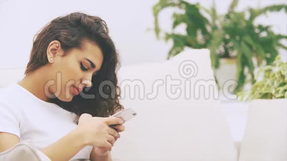 可爱古怪的美国黑人女孩正坐在沙发上手里拿着电话发着短信视频的预览图