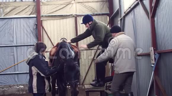 在专门的机库里一个有假肢的青年残疾人在严密的监护下学会骑马视频的预览图