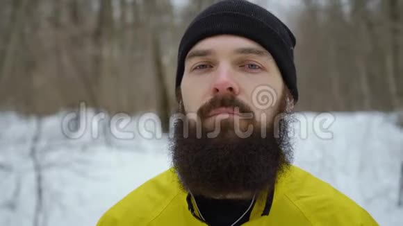 冬天森林里站着蓝眼睛和胡子的时髦男人的特写镜头视频的预览图