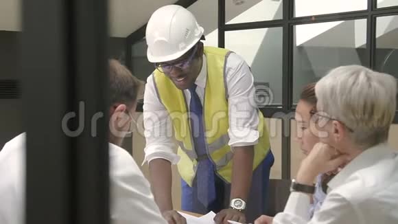 非洲工程师在头盔和一组建筑师讨论项目在会议室视频的预览图