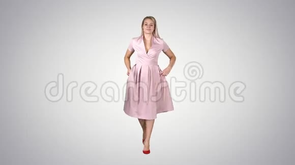 穿着粉红色衣服的女人双手插在口袋里正在渐变背景上朝镜头走去视频的预览图